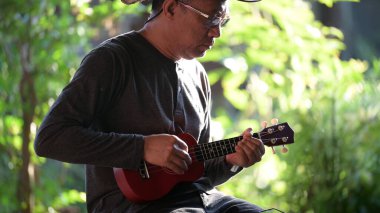 Genç adam parkta gitar çalıyor.