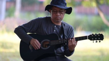 bir adam parkta gitar çalmak