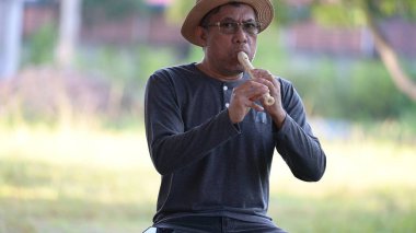 Elinde bir şişe su olan Asyalı kıdemli bir adam.