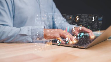 Profesyonel, yüzen analitik veri görselleriyle çevrili dizüstü bilgisayarla aktif olarak ilgilenmektedir. Görüntü, teknoloji ve veri analizinin modern çalışma ortamlarına entegrasyonunu vurgular.