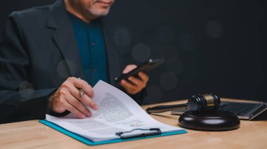 İlerlemedeki Hukuki Danışmanlık, akıllı telefonla uğraşırken hukuki belgeleri gözden geçirir, geleneksel ve modern yasal uygulamaların karışımını vurgular
