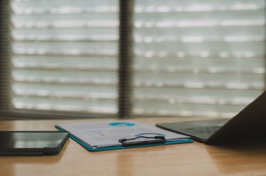 Modern Çalışma Alanı Özellikleri, ahşap masa üzerinde pano, akıllı telefon ve dizüstü bilgisayarın yer aldığı iyi organize edilmiş çalışma alanı, üretkenlik ve yaratıcılık için mükemmel bir ortam sağlıyor.