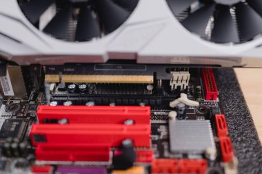 Bilgisayar Grafik Kartı ve Anakart 'ın yakın çekimleri, renkli ana karta güvenli bir şekilde yerleştirilmiş ayrıntılı grafik kartı, elektronik bileşenleri vurguluyor ve bilgisayar güncellemeleri için gerekli yuvaları vurguluyor