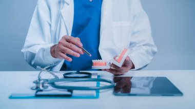 Profesyonel Diş Bakımı Mavi Temizlik Giysisi Uzmanı Büyüteç, Diş Temizleme Modeli Beyaz Masası Diş Sağlığı ve Parlak Klinik Arkaplan Testi