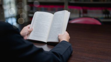 Derin düşüncelere dalmış karanlık sahne açık kitap, Bokeh ışıkları ve yumuşak yazı, ahşap masa arkasında entelektüel arayışlar için mükemmel.