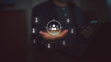 İş adamının elinde holografik hedef şahıs simgesine odaklanmış durumda. Müşteri ilişkileri yönetimi, insan kaynakları, pazarlama segmentasyonu, hedef iş stratejisi bulgularını temsil eder