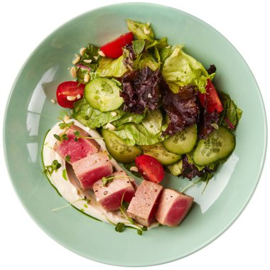 Az pişmiş ton balığı dilimleri ve taze sebze salatası. Beyaz arkaplanda izole