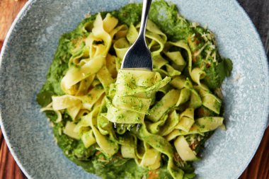 Pesto soslu Fettuccine makarna ve gri kasede parmesan peyniri..