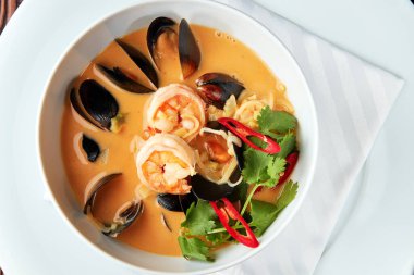 Tom Yam karides, midye, hindistan cevizi sütü ve biberli beyaz kasede baharatlı Tayland çorbası..