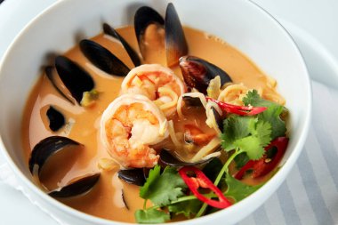 Tom Yam karides, midye, hindistan cevizi sütü ve biberli beyaz kasede baharatlı Tayland çorbası..