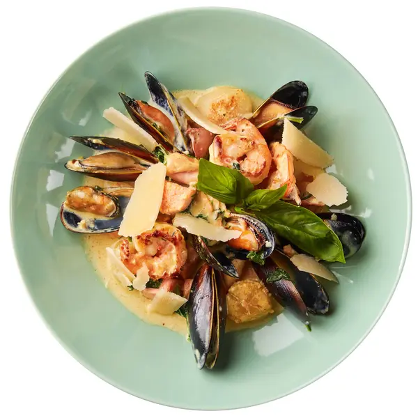 Çeşitli deniz ürünleri, midye, kalamar, deniz tarağı, somon filetosu ve sarımsaklı krem soslu kaplan karidesi, parmesan peyniri ve fesleğen. Beyaz arkaplanda izole