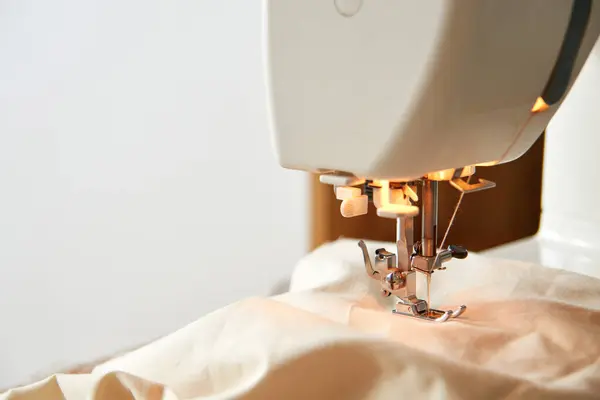 Sewing machine with piece of beige fabric, tailor workplace.