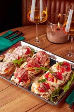 Pirzola, prosciutto, ançüez, domates, roka ve ahtapot dilimlenmiş. Şarap ile servis edilir.. 