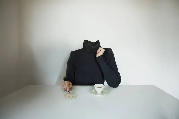headless surreal woman draws a smile emoji on the table with coffee, concept of communicating one\'s mood