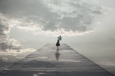 surreal woman with butterfly wings walks free on a jetty leading to the sea, abstract concept