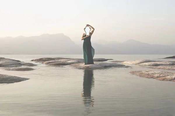 一个超现实的女人 她的脸上挂着一面镜子 倒映在一个迷人的湖水里 — 图库照片