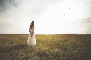 Doğanın ortasında batan güneşe büyülenmiş bir kadın.