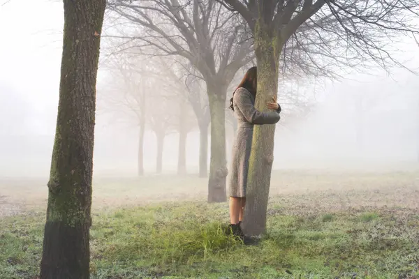 女人用爱心拥抱着树干象征生命 抽象的概念 图库图片