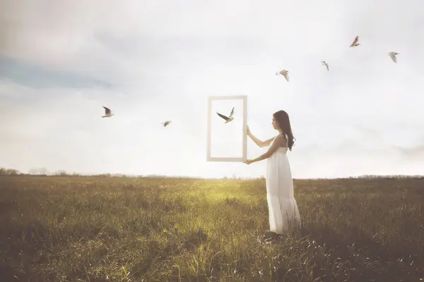 stock image woman holds a surreal window through which a group of birds pass by