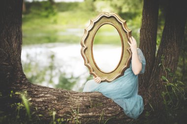 woman holding a mirror reflecting the nature behind, abstract concept clipart