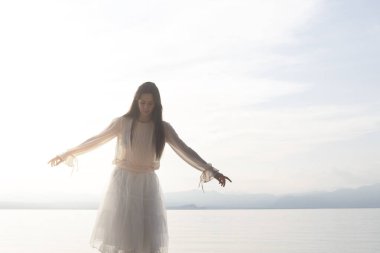 Kayalıklarda dengede duran bir kadın sırtını deniz manzarasına çeviriyor. Özgürlük kavramı.