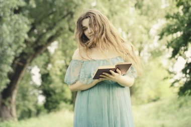 elegant woman reads a book walking in a meadow clipart