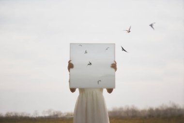 Yüzünün önünde tuval olan bir kadın. Hangi kuşların tarlada uçtuğu.