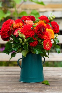 Tahta bir masanın üzerinde bir sürü kırmızı yıldız çiçeği olan sonbahar çiçeği buketi