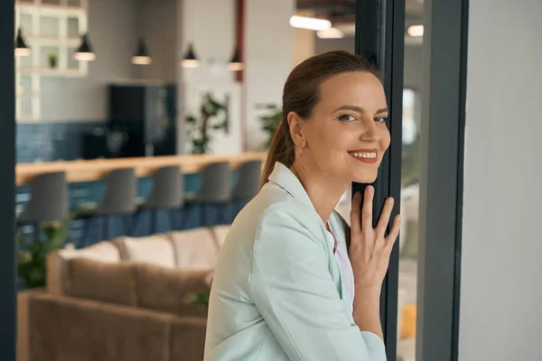 一个微笑优雅的女人站在玻璃门前与同事一起工作的咖啡馆的画像 — 图库照片