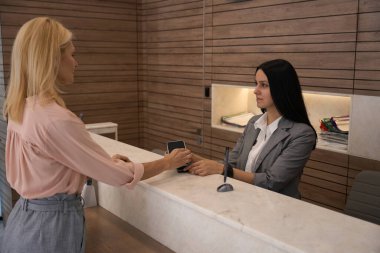 Müşteri, danışma masasındaki ulaşılamaz teknolojiyi kullanarak cep telefonuyla hizmet ödüyor.