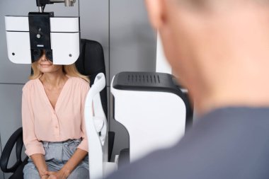 Sandalyeye oturup hastanedeki özel göz doktoruna bakan bir kadının portresi.