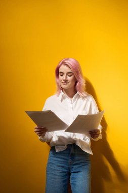 İş kadını, sarı parlak bir geçmişi olan, elinde kağıtlarla ofiste duruyor ve ona bakıyor.