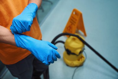 Sorumluluk sahibi hademenin temizlik sırasında koruyucu ekipman olarak lastik eldiven taktığı kesilmiş bir fotoğraf.