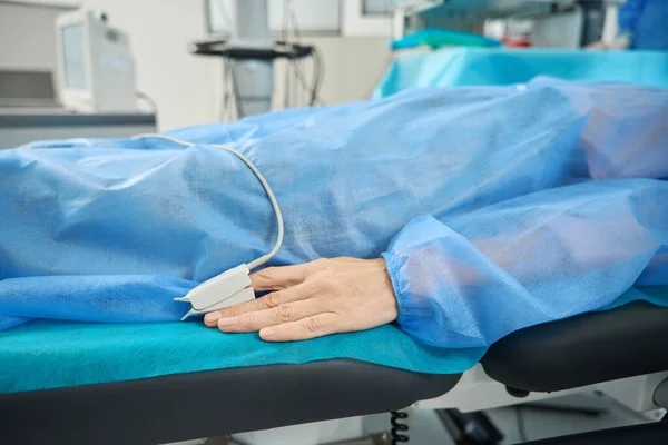 Patient Blauem Schutzanzug Liegt Mit Pulsoximeter Finger Auf Medizinercouch Operationssaal — Stockfoto