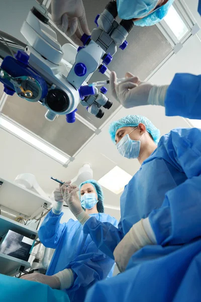 持有医疗器械和进行外科手术的身着防护服和戴口罩的医护人员的近照 — 图库照片