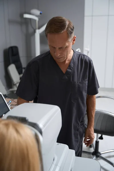 Siyah Ceketli Bir Tıp Çalışanı Otorefraktometreye Bakıyor Görüş Kontrolü Yapıyor — Stok fotoğraf
