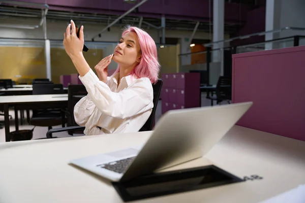 漂亮的女人 一头粉红的头发坐在桌旁 带着笔记本电脑 手牵着手 化着妆 — 图库照片