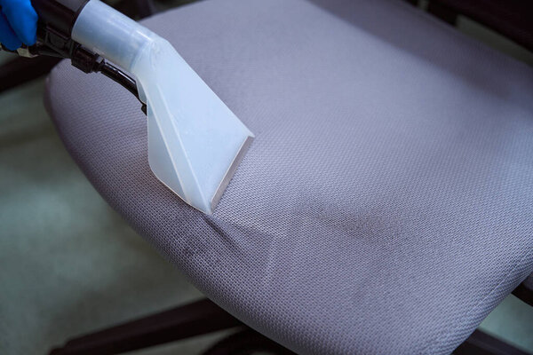 Close-up photo of upholstery vacuum-cleaner nozzle being used on top of a chair