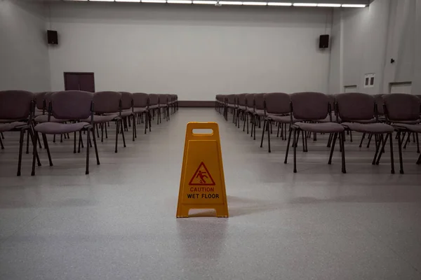 No people photo of yellow caution sign in the middle of a room full of chairs