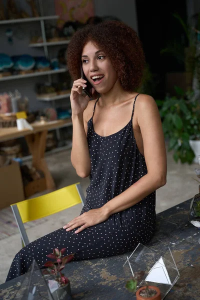 Jovem Excitada Tendo Uma Conversa Telefônica Sorrindo Amplamente Enquanto Senta — Fotografia de Stock