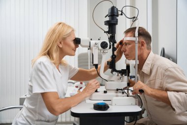 Doktor hastanın karşısındaki masada oturuyor ve sikloskopi yapmak için goniolen kullanıyor.