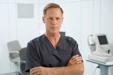 Ofiste dikilip kameraya bakan orta yaşlı doktor portresi.