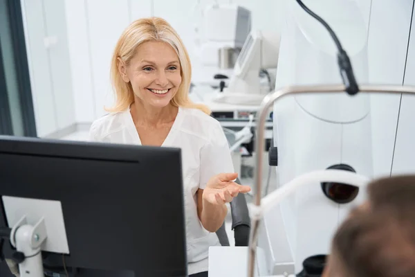 Usmívající Zdravotník Bílém Plášti Sedí Počítače Mluví Pacientem — Stock fotografie