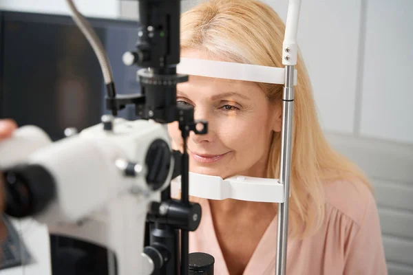 目の検査をしながら眼科室に座っている笑顔の女性のクローズアップ写真 — ストック写真