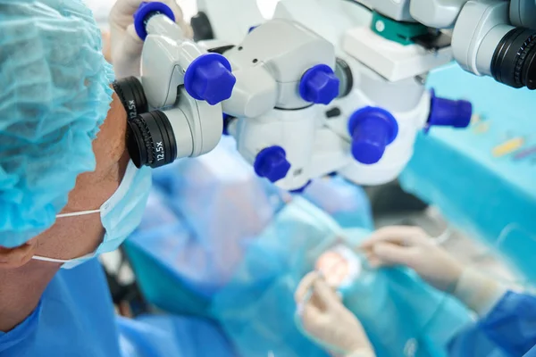 Korumacı Maskeli Şapkalı Bir Tıp Çalışanı Cerrahi Mikroskoba Bakıyor Hastaya — Stok fotoğraf