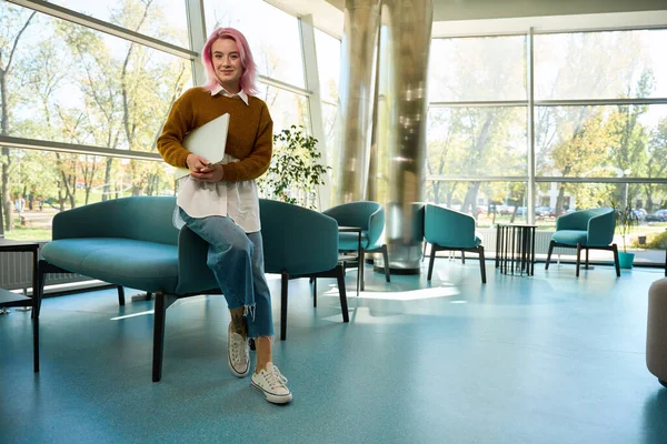 Молода Жінка Рожевим Волоссям Стоїть Біля Дивана Офісі Тримає Ноутбук — стокове фото