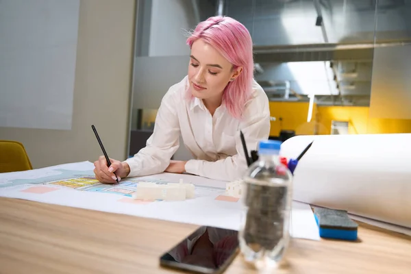 stock image Young architect with pink hair sitting by the table while working on architectural projects in coworking