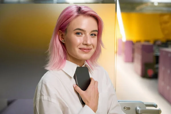 Молода Жінка Рожевим Волоссям Тримає Телефон Дивиться Камеру Коворкінгу — стокове фото