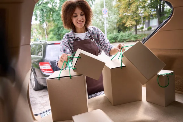 年轻的 面带微笑的女商人正在把装有纸板箱的汽车行李箱装上 以便向买家下订单 — 图库照片