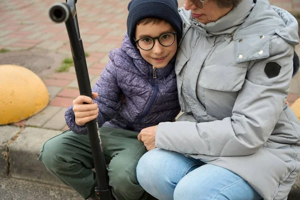 Happy Granny Winter Clothes Sitting Curb Child Holding Scooter Hugging — Stock Photo, Image